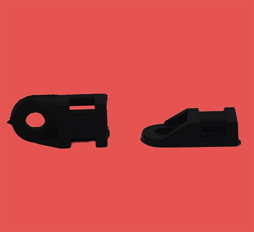 Two black cable tie eyelets shown side by side, one in a flat side view and one in a top plan view, highlighting design and fastening points