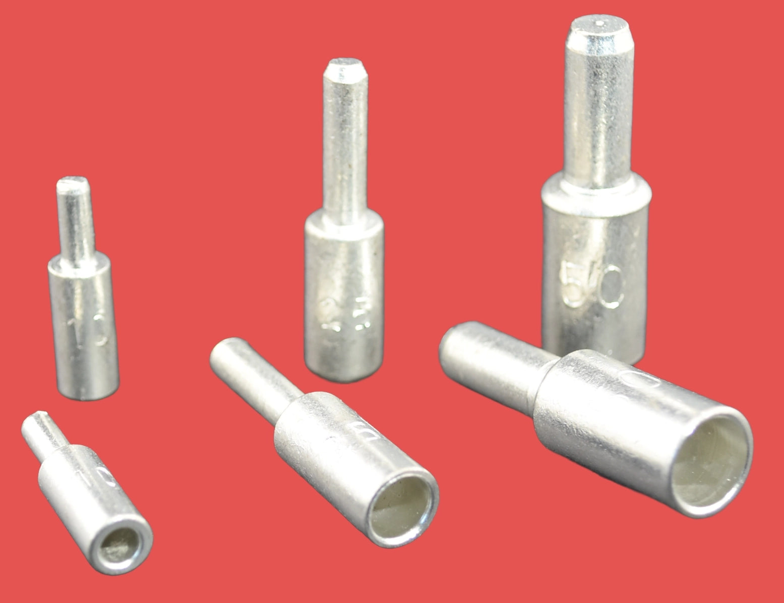 A set of copper tube pins of various sizes arranged against a red background.