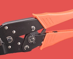 Professional insulated terminal crimper with black metal body and orange grip handles, featuring multiple crimping die sizes for red, blue, and yellow insulated terminals, displayed on coral background